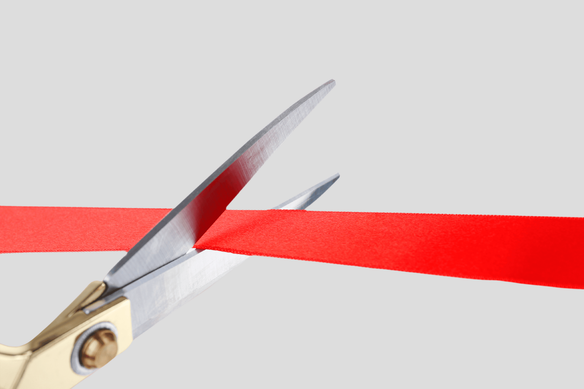 En saks som klipper et JM Band® Innvielsesbånd med Fargetrykk-bånd.