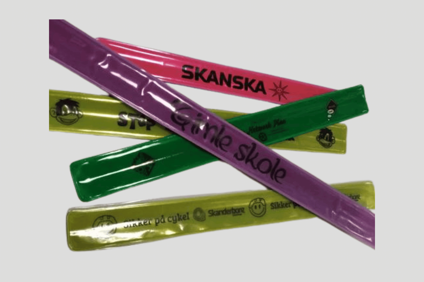En gruppe fargerik plast Slap armbånd trykk laget av PVC-materiale, hver prydet med ordet JM Band® silketrykt på dem.